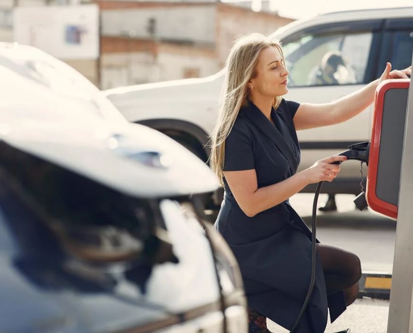 Ung kvinde sætter sin elbil til opladning