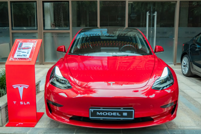 En rød tesla model 3 oplader