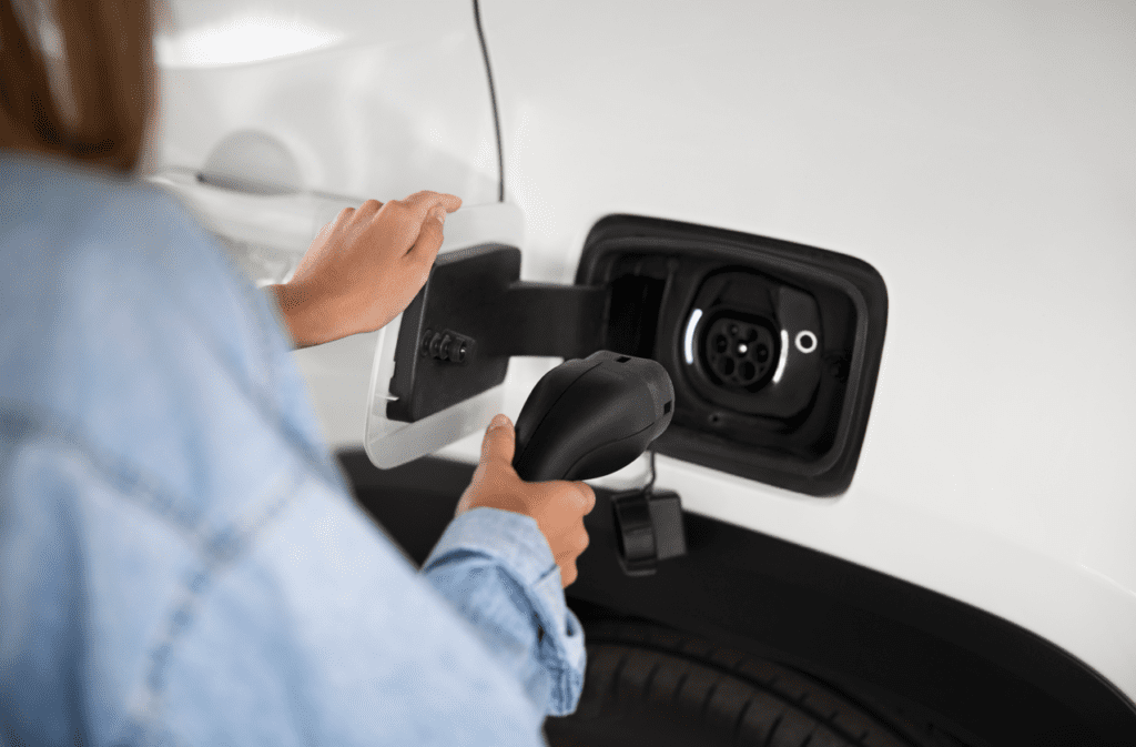 Kvinde oplader sin elbil i hvid